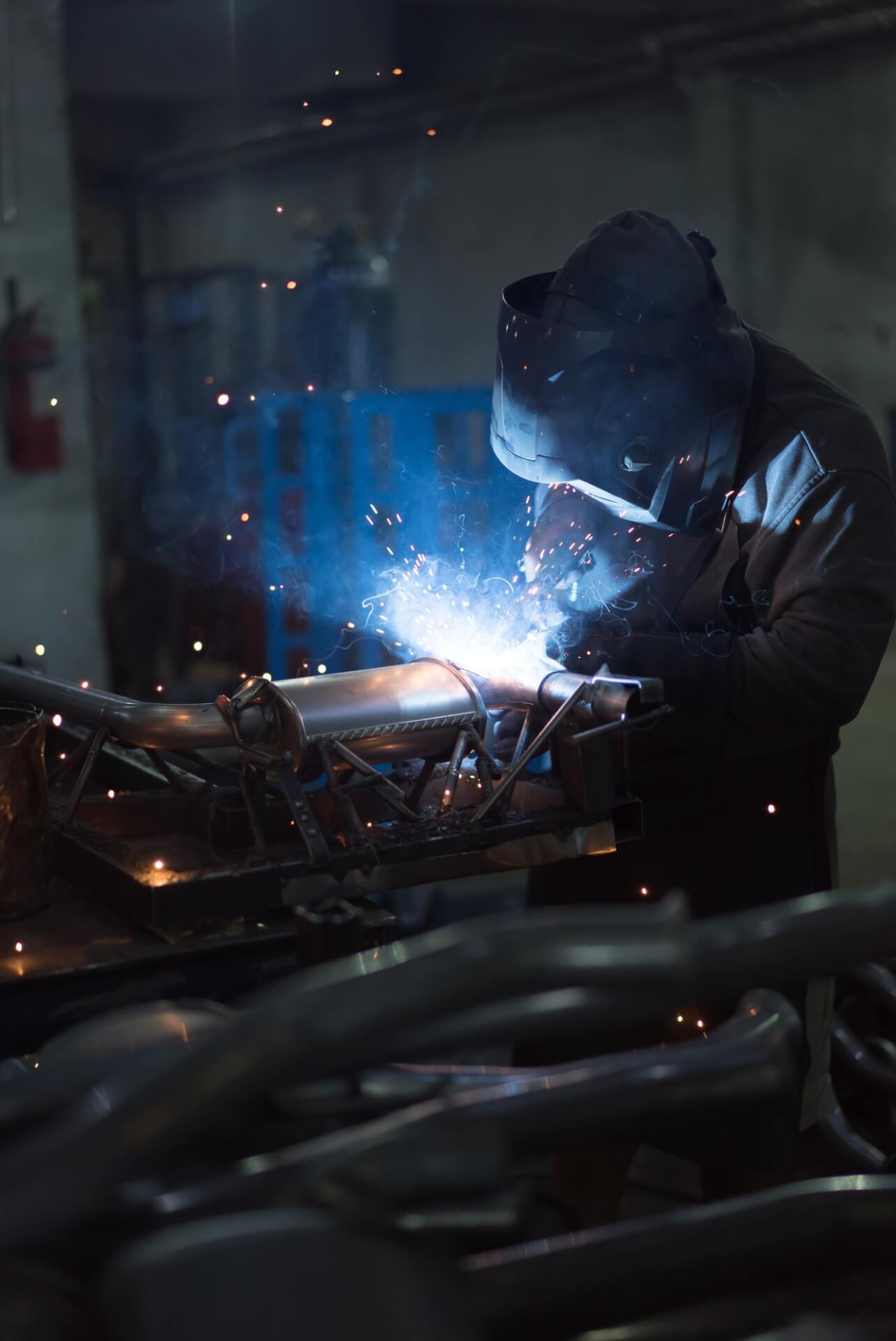 worker-welding-exhaust-pipes-pieces-together.jpg