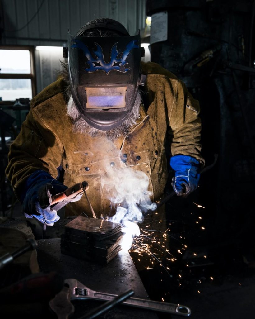 blacksmith-in-welding-mask-welding-metal-in-workshop.jpg blacksmith-in-welding-mask-welding-metal-in-workshop.jpg