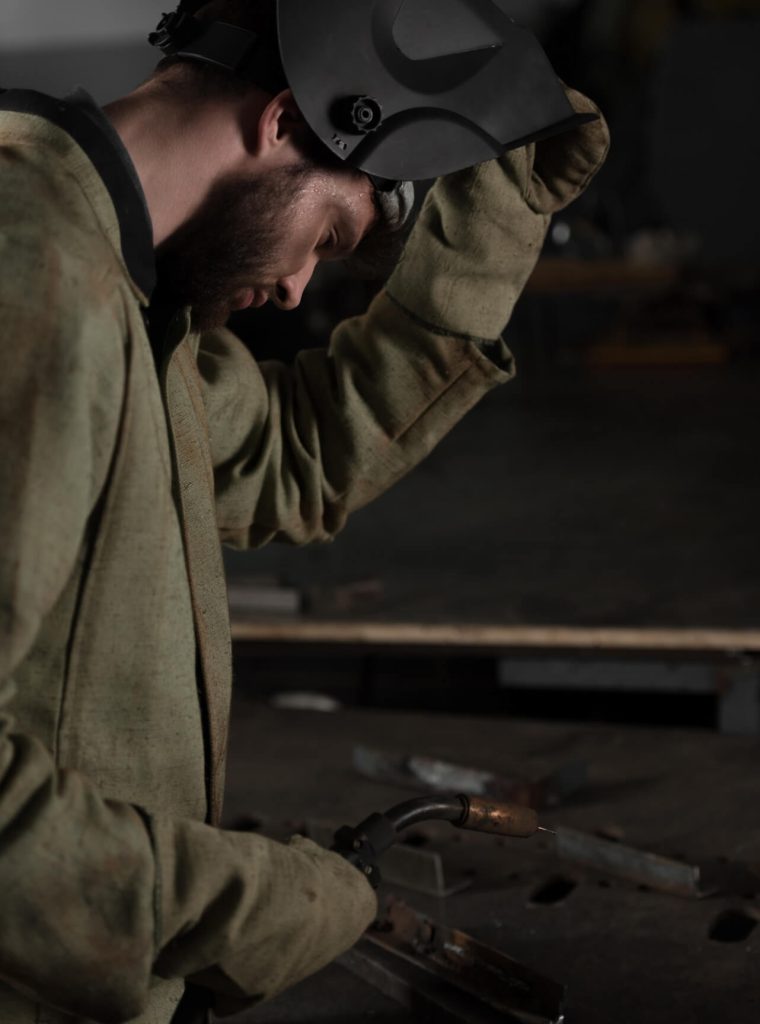 side-view-of-welder-lifting-up-protective-mask-to-look-at-his-work.jpg